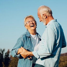 An older couple smiling and laughing outdoors