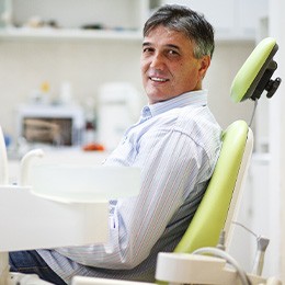 Older man sitting in dental chair and smiling