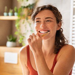 Woman in red shirt brushing her teeth
