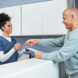 Man filling out paperwork at dental office front desk