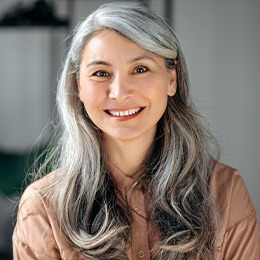 A smiling, grey-haired senior in a business setting