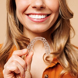 Smiling patient holding clear aligner