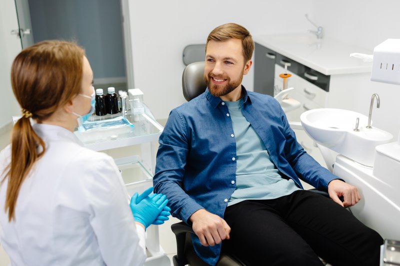 A smiling, bearded man talking to his cosmetic dentist